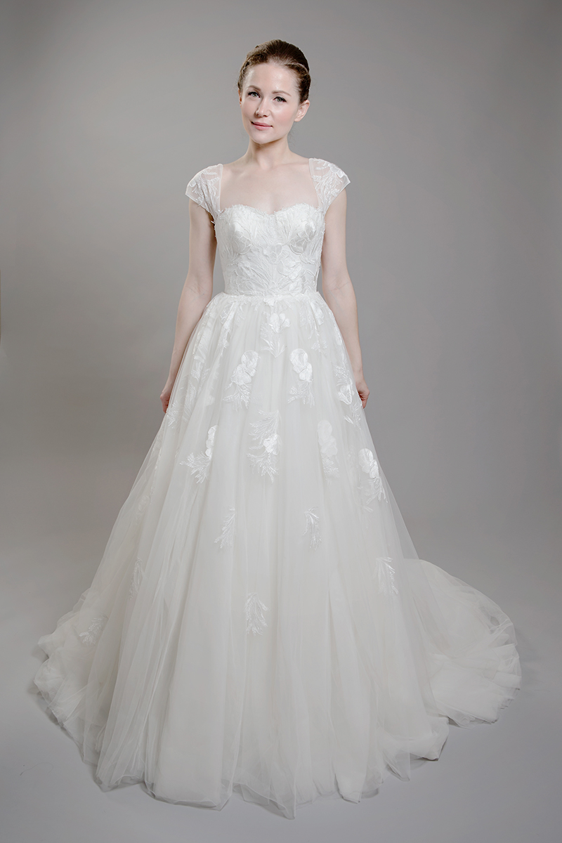F1607 is a beautiful tulle and lace dress that requires no beading to enhance its beauty. The lace is a tulip design, with the bust being a full tulip and the leaves falling down the skirt. It has detachable cap sleeves